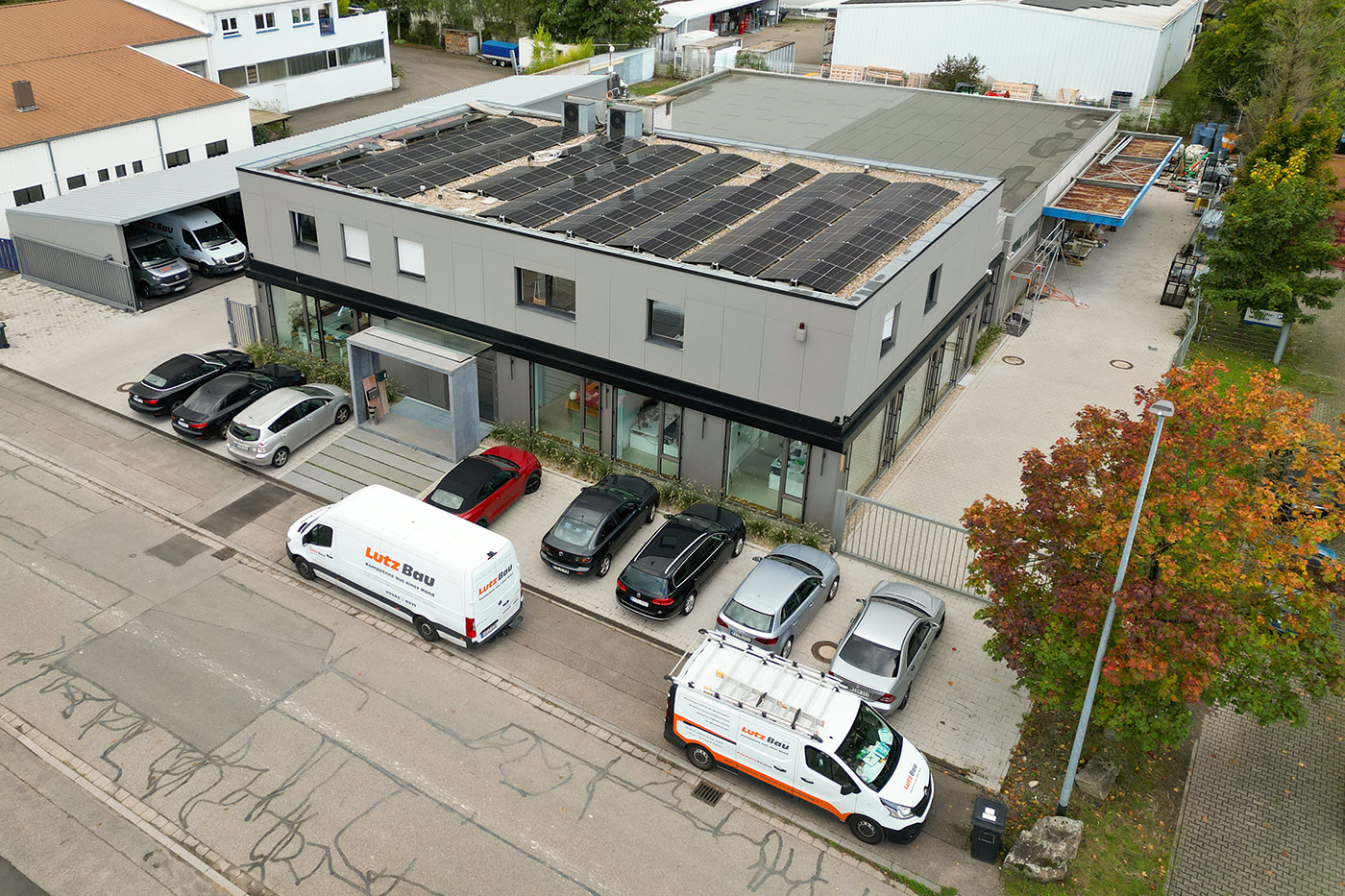 Drohnenaufnahme einer Gewerbeimmobilie mit Solardach und Firmenfahrzeugen